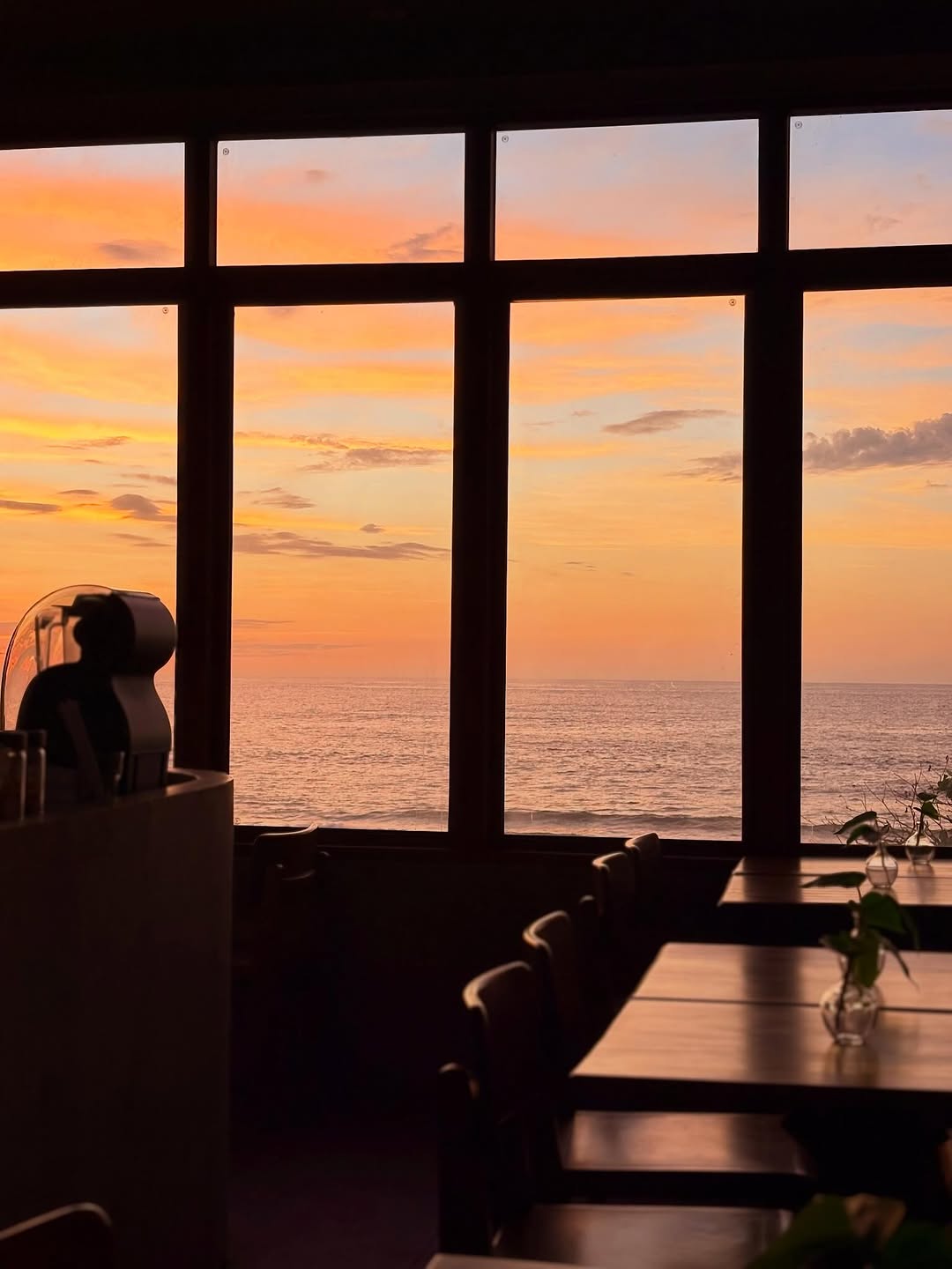 UNA restaurant dining room at golden hour — large grid windows framing the South China Sea