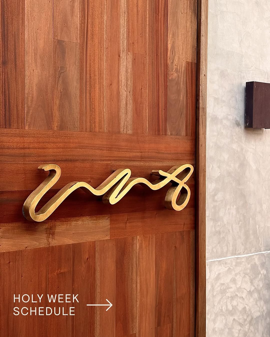 Gold UNA logo signage on wood wall